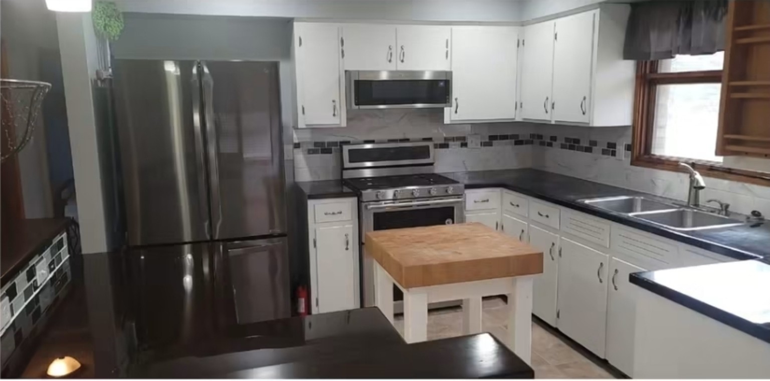 Completed kitchen remodel with white cabinetry, dark counters, and stainless appliances
